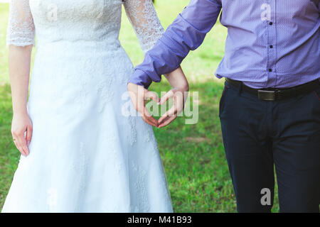 Die Braut und der Bräutigam halten die Hände in der Form des Herzens. Stockfoto
