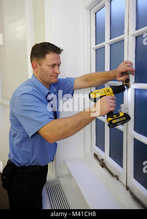 Mann zur Festsetzung ein Sicherheitsschloss an ein Fenster. Stockfoto