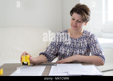 Frau einzelner Unternehmer setzt eine Dichtung auf einem Dokumente Stockfoto