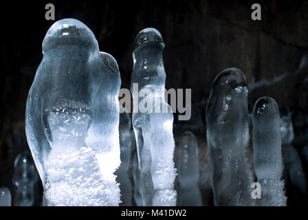 Gruppe von transparenten Eis Stalagmiten in einer Höhle Nahaufnahme auf einem dunklen Hintergrund Stockfoto