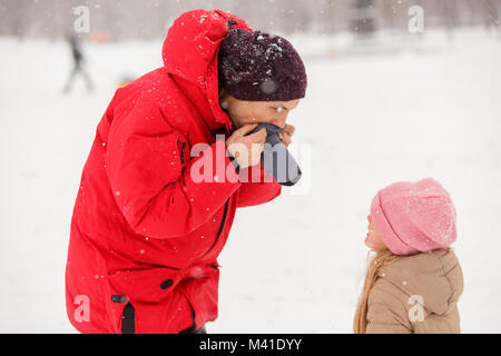 Foto von Vater dressing seiner Tochter mitten im Winter Park Stockfoto