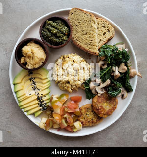 Vegan Tofu mit Avocado, Brot, Gemüse und Quelle close-up auf einem Teller. Stockfoto