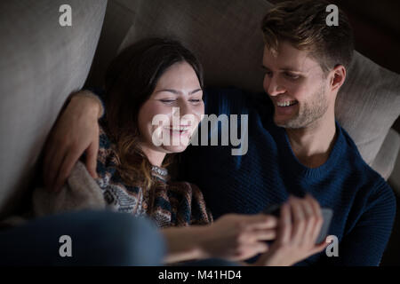 Paar auf Smartphone auf dem Sofa Stockfoto