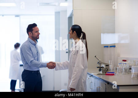 Wissenschaftlerin Händeschütteln mit pharmazeutischen Vertriebsmitarbeiter Stockfoto