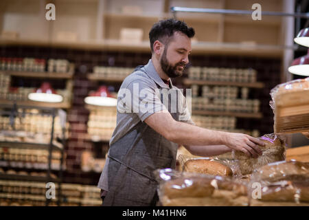 Bäcker in der Bäckerei Strumpf Regale und Blick in die Kamera Stockfoto