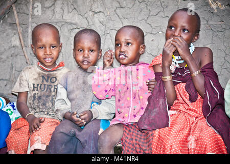 Afrika, Tansania - Februar 9, 2014: Portrait auf einer afrikanischen Kinder der Massai Stamm Dorf lächelnd in die Kamera, das Leben in Haus mit Kuhmist, Fe Stockfoto