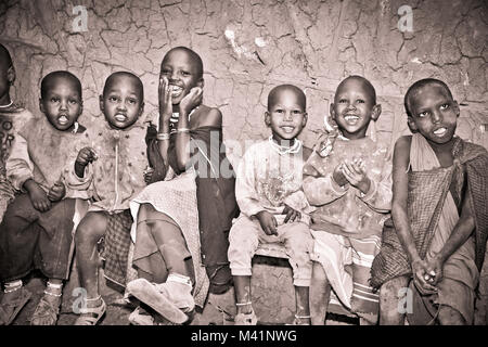 Afrika, Tansania - Februar 9, 2014: Portrait auf einer afrikanischen Kinder der Massai Stamm Dorf lächelnd in die Kamera, das Leben in Haus mit Kuhmist, Fe Stockfoto