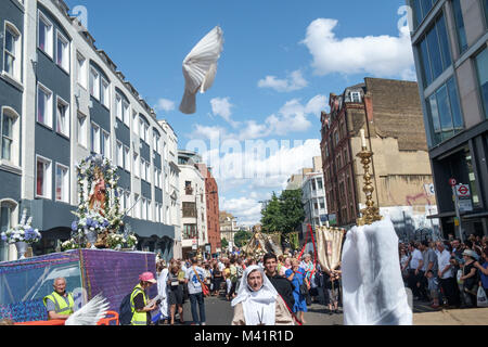 Tauben sind zu Beginn der Prozession während das Fest Unserer Lieben Frau vom Berge Karmel in der Italienischen Kirche in Clerkenwell freigegeben. Eine fans seine Flügel in der Luft und anderen Dateien low auf der rechten Seite, ein Flügel nur vivible. Stockfoto