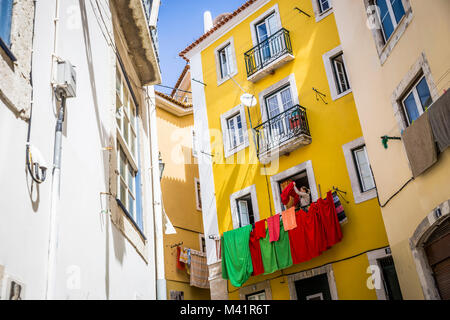 Eine Frau hängt Wäsche auf ihrem Balkon in Lissabon, Portugal. Stockfoto