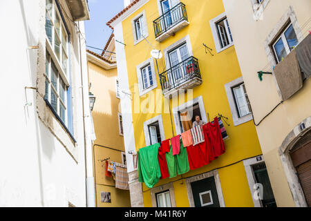 Eine Frau hängt Wäsche auf ihrem Balkon in Lissabon, Portugal. Stockfoto