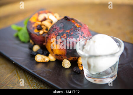 Gegrillte Pfirsiche mit Muttern und Eis Stockfoto