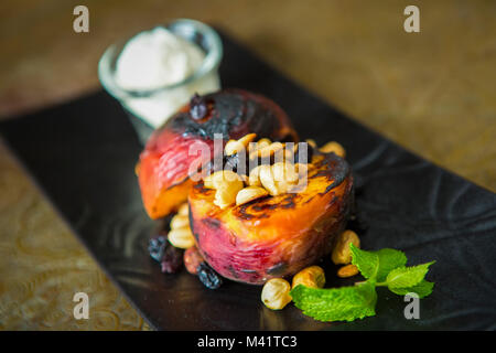 Gegrillte Pfirsiche mit Muttern und Eis Stockfoto