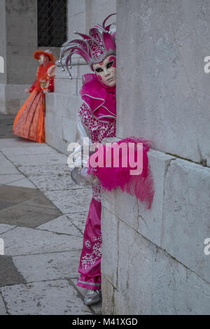 Frau verkleidet als Hofnarr in rosa Kostüm an der Kirche San Giorgio Maggiore auf die Insel San Giorgio während der Karneval von Venedig das Posieren. Stockfoto