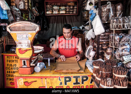 Ein Mann, der eine Weste hand-gerollte Zigarren in einem Stall in einem Markt, in Asuncion, Paraguay Stockfoto