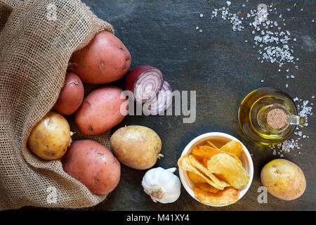 Ansicht von oben der Kartoffeln mit Chips, roten Zwiebeln, Olivenöl, Knoblauch und Salz, auf schiefer Tisch mit Platz kopieren Stockfoto