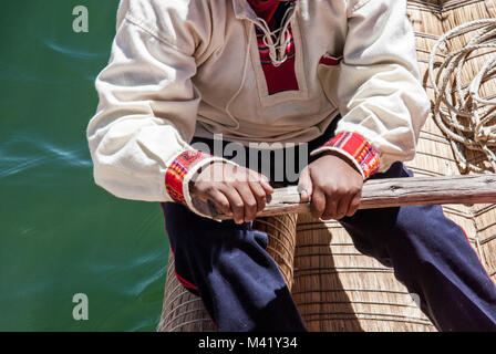 Eine peruanische Mann in traditioneller Kleidung mit einem Holz- oar ein Boot von Schilf zu Zeile Stockfoto