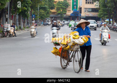 Lokale Vietnamesin Bananen verkaufen von Ihrem Fahrrad auf den Straßen von Hanoi, Vietnam Stockfoto