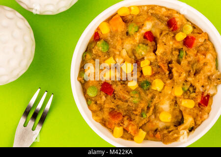 Traditionelle Shepards Pie und Gemüse in eine Schüssel vor einem grünen Hintergrund Stockfoto