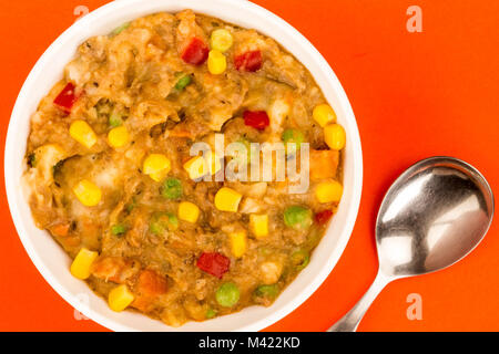 Traditionelle Shepards Pie und Gemüse in einer Schüssel auf rotem Hintergrund Stockfoto