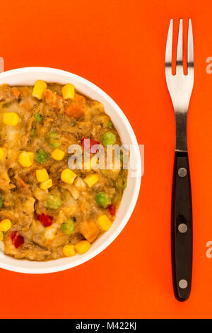 Traditionelle Shepards Pie und Gemüse in einer Schüssel auf rotem Hintergrund Stockfoto