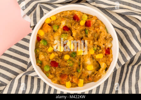 Traditionelle Shepards Pie und Gemüse in einer Schüssel gegen einen rosa Hintergrund Stockfoto