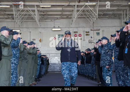 NORFOLK, Virginia (Feb. 8, 2018) - Chief Warrant Officer Ernest Brinson, auf USS Gerald R. Ford's (CVN 78) Combat Systems Abteilung zugewiesen, kehrt die Salute von Ford Segler, als er das Schiff fährt. (U.S. Marine Foto von Mass Communication Specialist 2. Klasse Kiana A. Raines) (Abzeichen in diesem Foto haben für Zwecke der Sicherheit verwischt worden) Stockfoto