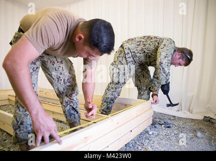 FUJAIRAH, Vereinigte Arabische Emirate (Jan. 13, 2018) Builder 3. Klasse Hilario Hernandez und Steelworker 3. Klasse Ethan Holz-, U.S. Navy Sailors zu Amphibischen Bau Bataillon 1 angeschlossen ist, bauen Bodenbeläge Bilder während der nativen Wut 18. Die Übung ist so konzipiert, Special Purpose Marine-Air - Masse Aufgabe Force-Native Fury Marines und US-Marine Seeleute in maritime Vorpositionierung kraft Operationen zu trainieren und zielt darauf ab, die Kenntnisse zu verbessern, erweitern die Zusammenarbeit im maritimen Fähigkeiten zu verbessern und die langfristige Stabilität in der Region und die Interoperabilität zwischen den Vereinigten Arabischen Emiraten und den US Stockfoto