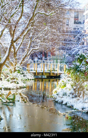 Kleiner Fluss mit mini Pont im Park, Outdoor in Paris, Frankreich, bei Schneefall im Winter. Am Morgen mit dem Sonnenaufgang das Licht genommen. Smart Concept Stockfoto