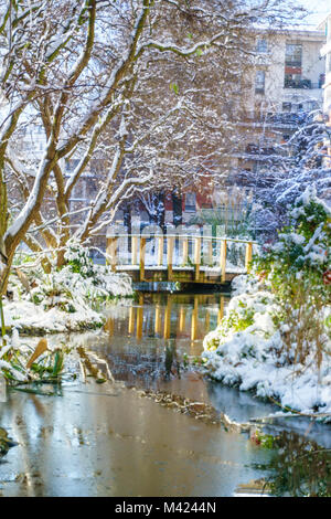 Kleiner Fluss mit mini Pont im Park, Outdoor in Paris, Frankreich, bei Schneefall im Winter. Am Morgen mit dem Sonnenaufgang das Licht genommen. Smart Concept Stockfoto