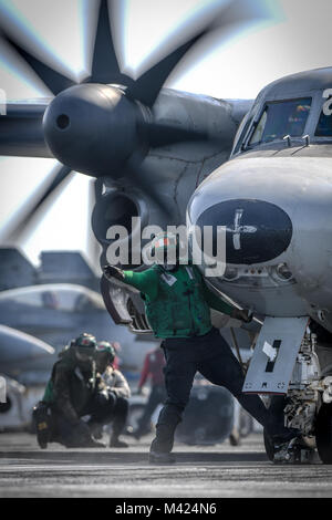 180210-N-MJ 135-1044 arabischen Golf (Feb. 10, 2018) der Luftfahrt Bootsmann Mate (Ausrüstung) Airman Robert Rodriguez Signale an eine E-2C Hawkeye, zugeordnet zu den Sunkings des Trägers Airborne Early Warning Squadron (VAW) 116, auf dem Flugdeck der Flugzeugträger USS Theodore Roosevelt (CVN 71) starten. Theodore Roosevelt und ihre Carrier strike Group werden in den USA 5 Flotte Bereich für Maßnahmen zur Erhöhung der Sicherheit im Seeverkehr im Einsatz Verbündeten und Partnern zu beruhigen und der Freiheit der Schiffahrt und des freien Handels in der Region erhalten. (U.S. Marine Foto durch Massenmedien. Stockfoto