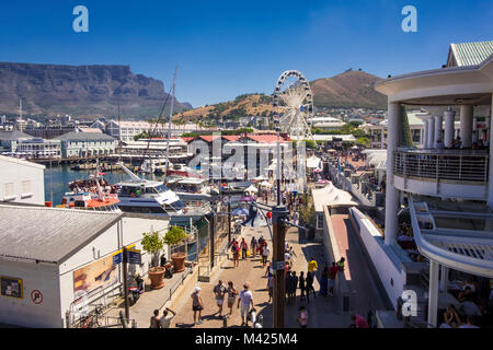 Kapstadt, Südafrika - Touristen und Shopper an der V&A Waterfront, mit Cape Union Mart, Cape Wheel und Table Mountain Stockfoto