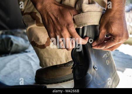 Tech Sgt. Kendrick Butler, 23 d Maintenance Squadron assistant NCO verantwortlich für Flugzeuge Metals Technology, strafft seine Stiefel, Feb 1, 2018, bei Moody Air Force Base, Ga Flieger in einer chemischen, biologischen, radiologischen und nuklearen Verteidigung (CBRNE) Klasse, besser zu bereiten feindliche Angriffe zu bekämpfen, während sie auch vertraut mit mission-orientierten schützende Haltung (MOPP) Gang. (Air Force Foto von Airman Eugene Oliver) Stockfoto