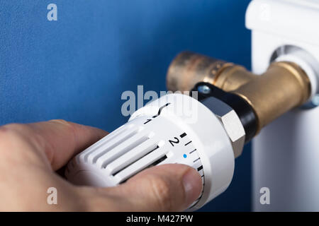 Person's Hand Einstellen der Temperatur am Thermostat zur Steuerung der Hitze in Zentralheizung Stockfoto