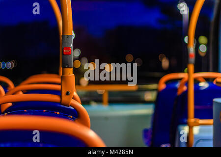 Innenraum der typisch britischen Bus mit Sitzgelegenheiten und die rote Taste Stopp bei Nacht, Devon, Großbritannien. Feb 2018. Stockfoto