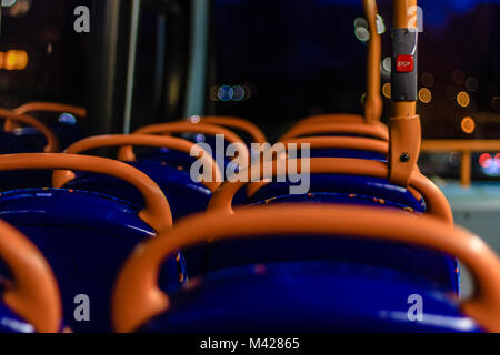 Innenraum der typisch britischen Bus mit Sitzgelegenheiten und die rote Taste Stopp bei Nacht, Devon, Großbritannien. Feb 2018. Stockfoto