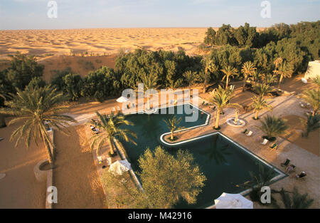 Tunesien. Oase Ksar Ghilane. Sahara. Swimmingpool im Hotel. Hintergrund Sanddünen. Stockfoto