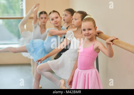 Süße Ballerina in rosa Kleid im Studio. Junge Ballerinas in schönen Kleidern, die an Ballet Barre im Studio. Stockfoto