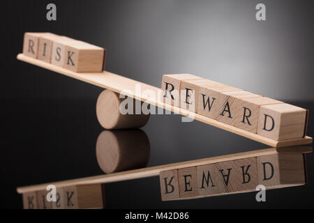 Nahaufnahme einer Holz- Wippe, Ungleichgewicht zwischen Risiko und Belohnung auf grauem Hintergrund Stockfoto