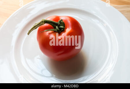 Eine große Rebe überreifen Tomate auf eine weisse Platte Stockfoto