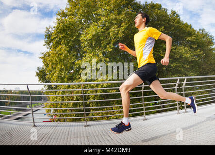 Seitenansicht Portrait von aktiven Mann über die Brücke im Freien im City Park Stockfoto