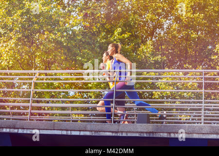 Seitenansicht Porträt des jungen Paares im Sport Outfit über eine Brücke im City Park Stockfoto