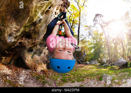 Süße Mädchen in Helm hanging upside-down beim Klettern Zug draussen im Wald Stockfoto