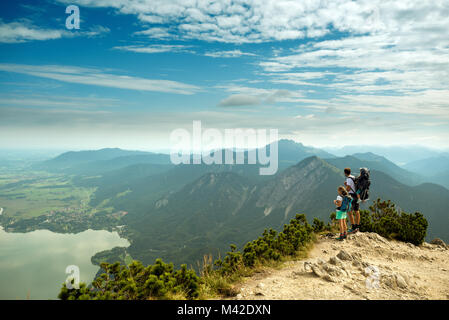 Mann mit Frau und Baby steht auf Herzogstand Aussichtspunkt in den deutschen Alpen Stockfoto