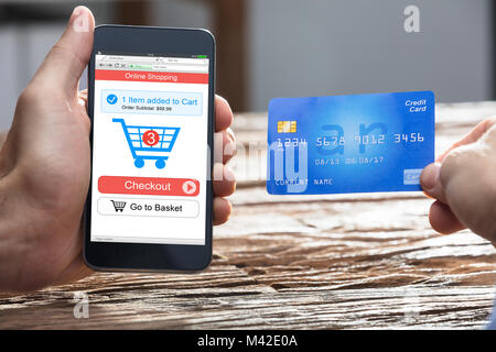 Der Unternehmer Hand tun, Online Shopping auf dem Smartphone mit EC-Karte über Holz- Schreibtisch Stockfoto