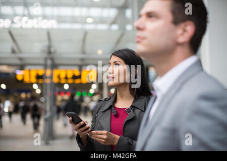 Pendler im Zug mal am Bahnhof holding Smartphone Stockfoto