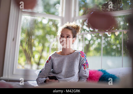 Teenager im Schlafzimmer halten Smartphone Stockfoto