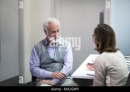 Weibliche Arzt hören ein älterer Patient Symptome Stockfoto