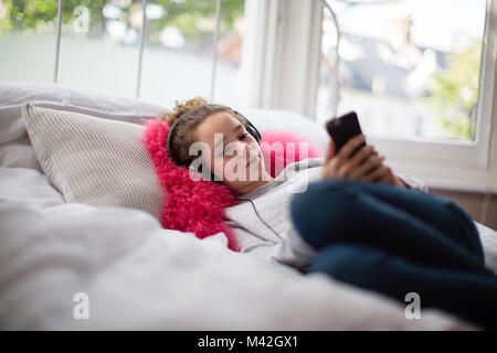 Teenager im Schlafzimmer hören von Musik auf dem Smartphone Stockfoto
