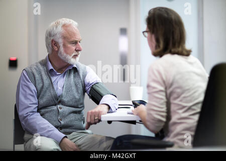 Weibliche Arzt, ein älterer Patienten Blutdruck Stockfoto