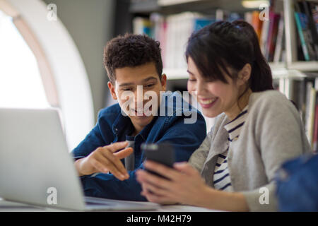 Studenten, die an Smartphone in Bibliothek Stockfoto